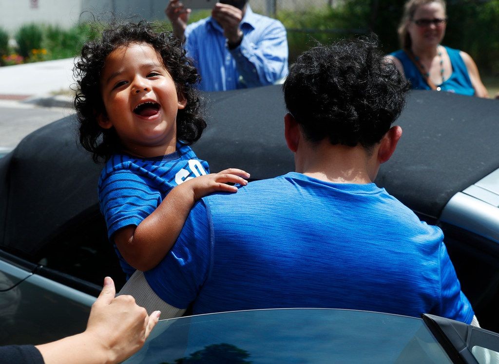 a child smiles as he is carried by his father 
