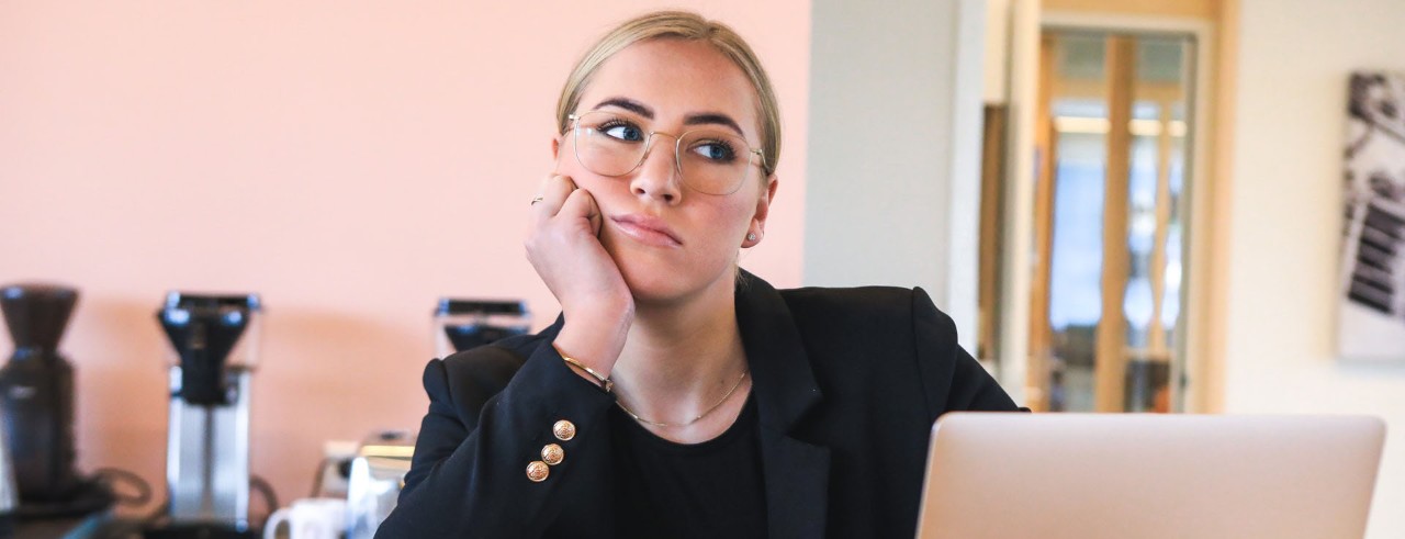 woman at desk with hand on chin looking off into the distance