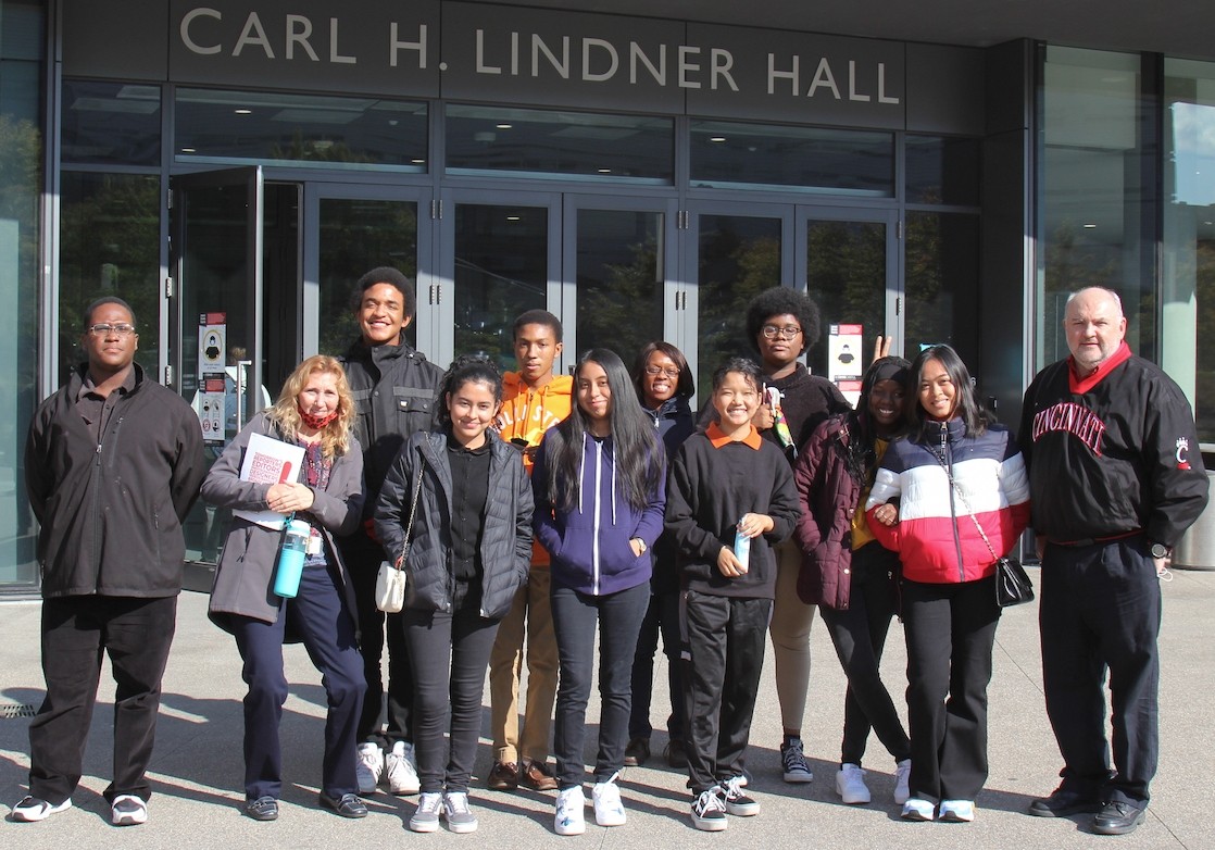 A group of students stand outside of a college.