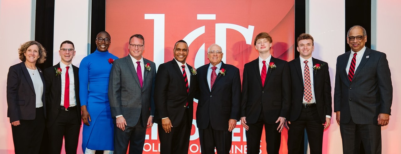 A group of men and women pose for a photo after an awards ceremony.