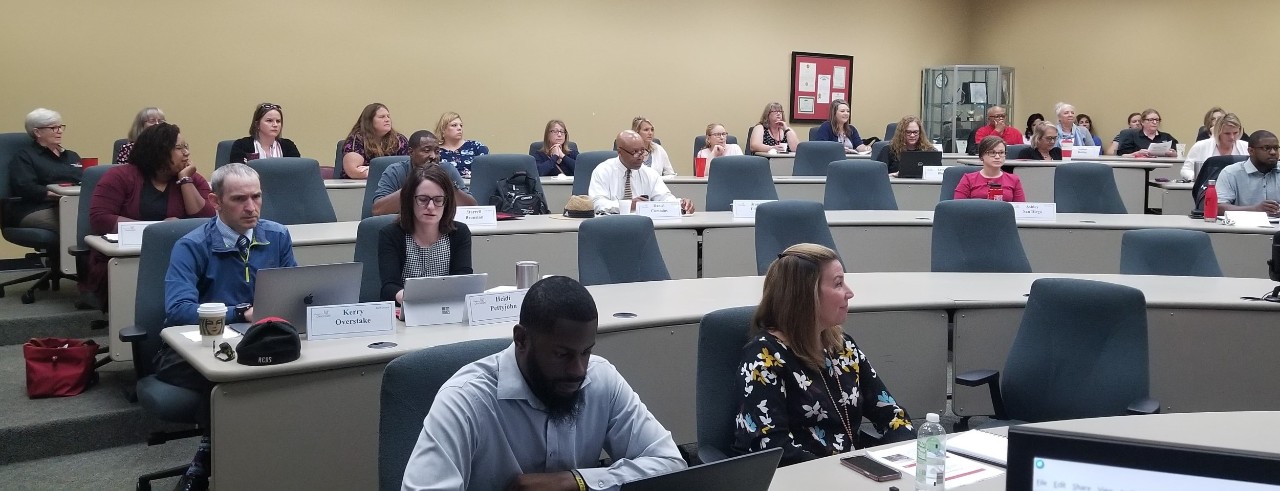 Staff seated at a meeting in a large classroom