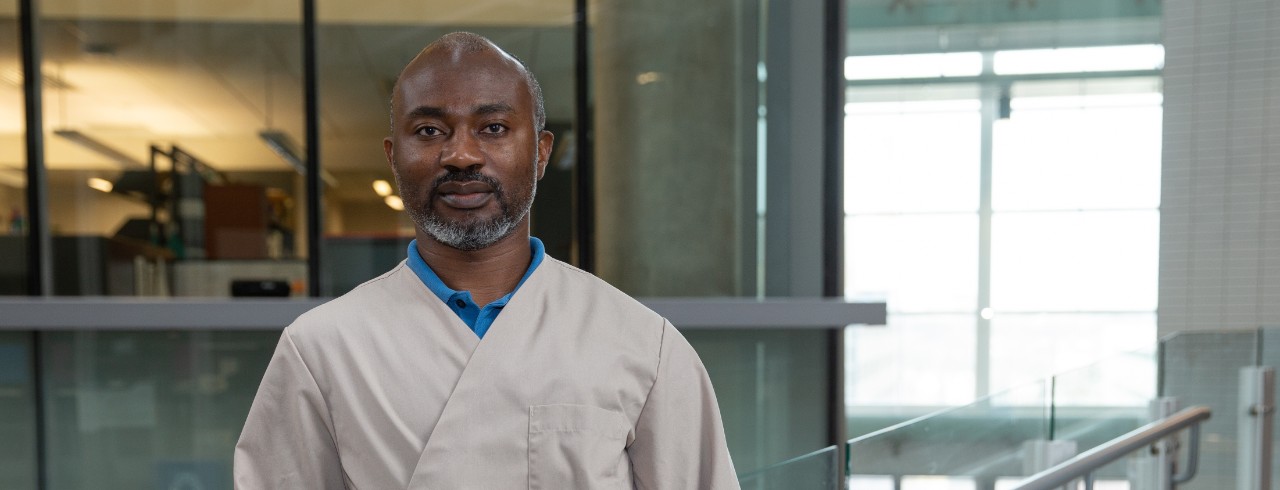 Portrait photo of Dr. Hyacinth standing on an indoor bridge