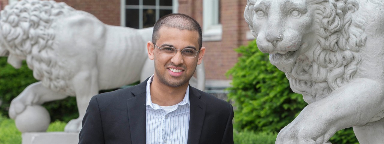 Student Chinmay Bakshi stands by the stone lions outside outside Arts & Sciences Hall, University of Cincinnati