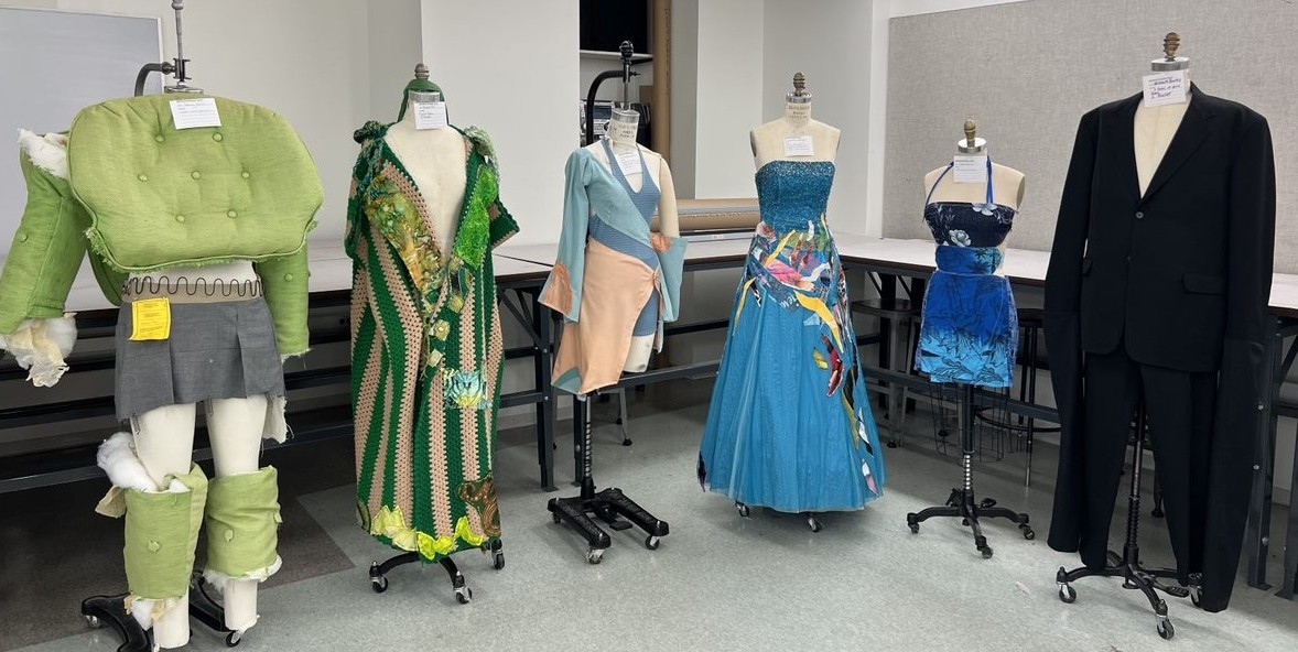 mannequins wearing fashion designs made from thrifted items. One outfit is made out of green couch cushions.
