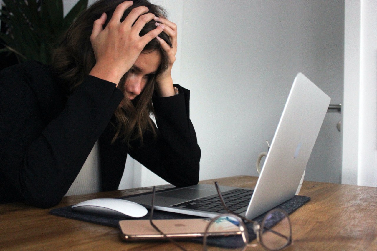 a woman looking stressed sitting in front of her laptop