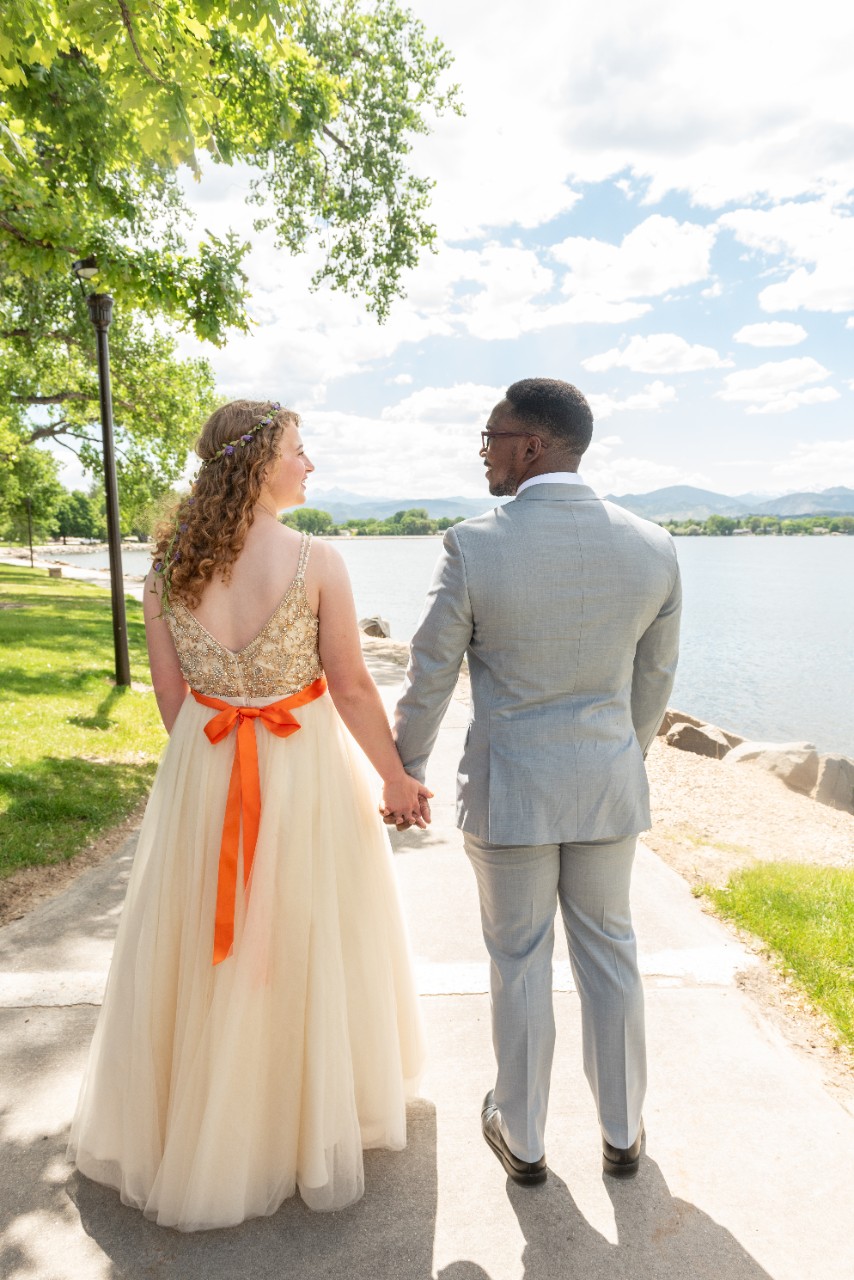 Zoe Lee and Christian Charles, in wedding gown and suit, stroll down a path holding hands.