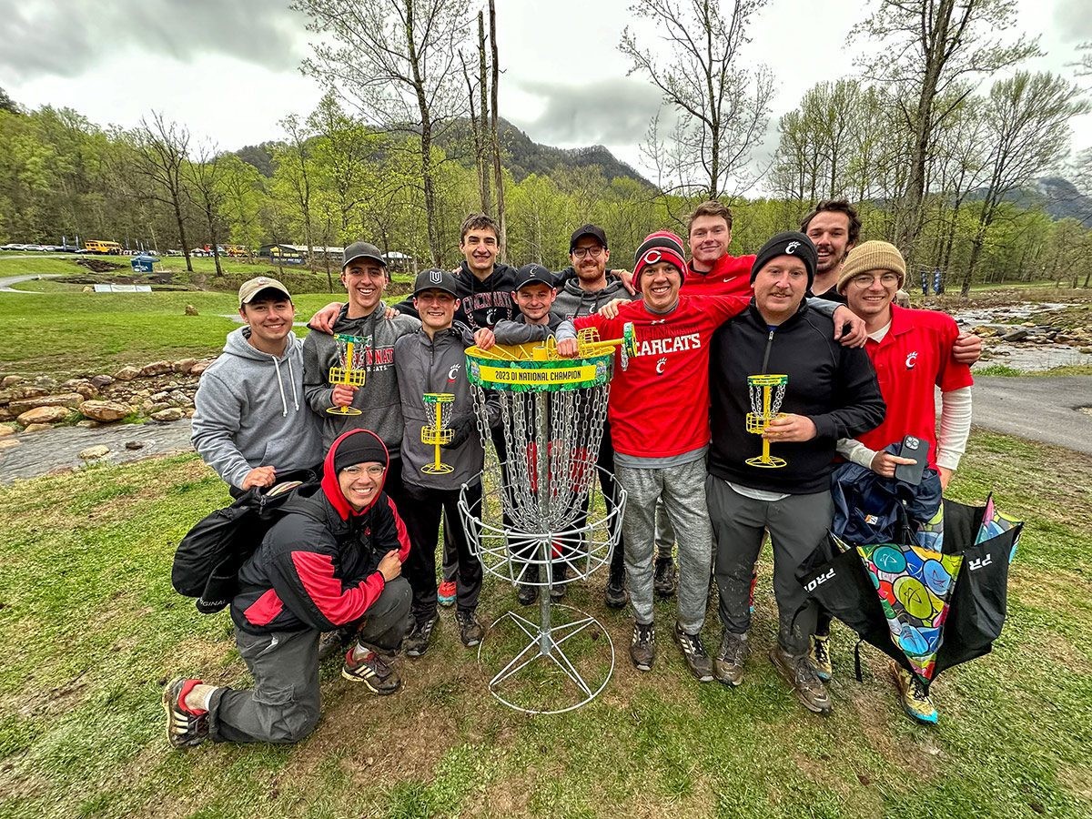 UC's disc golf team poses with the basket-shaped national championship trophy.
