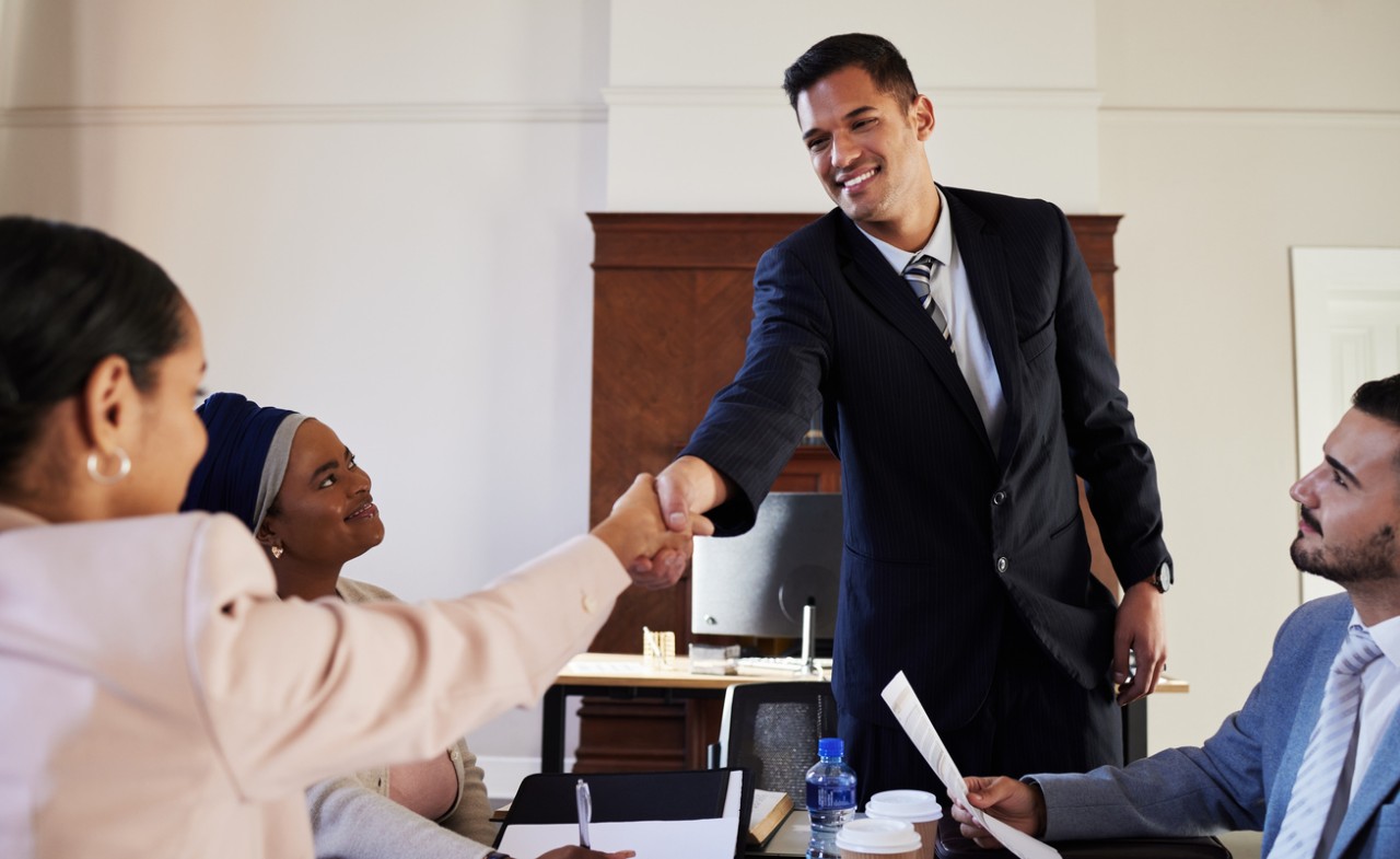 Law students at firm sitting at a table shaking hands