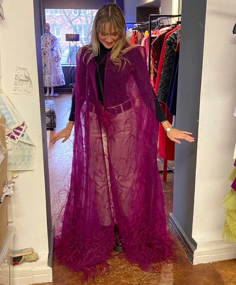 UC DAAP student Kathryn Suddendorf wears a purple couture cape with sewn on purple feathers.
