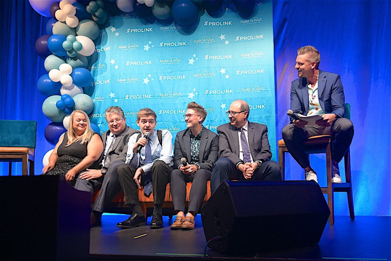 Six people sitting on chairs on a stage receiving awards