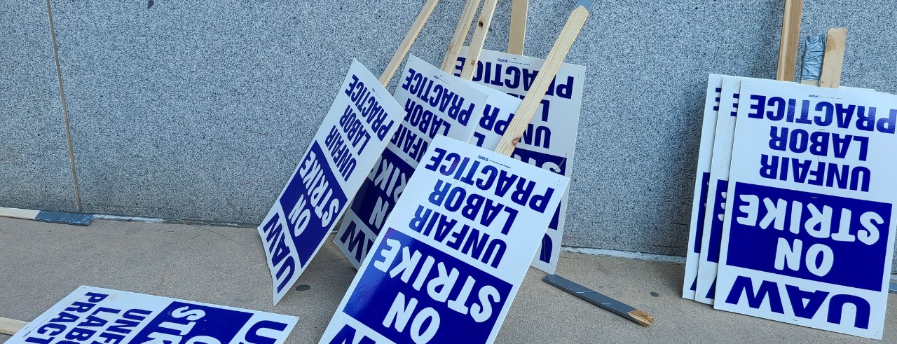 Labor union on strike picketing signs resting on a wall.