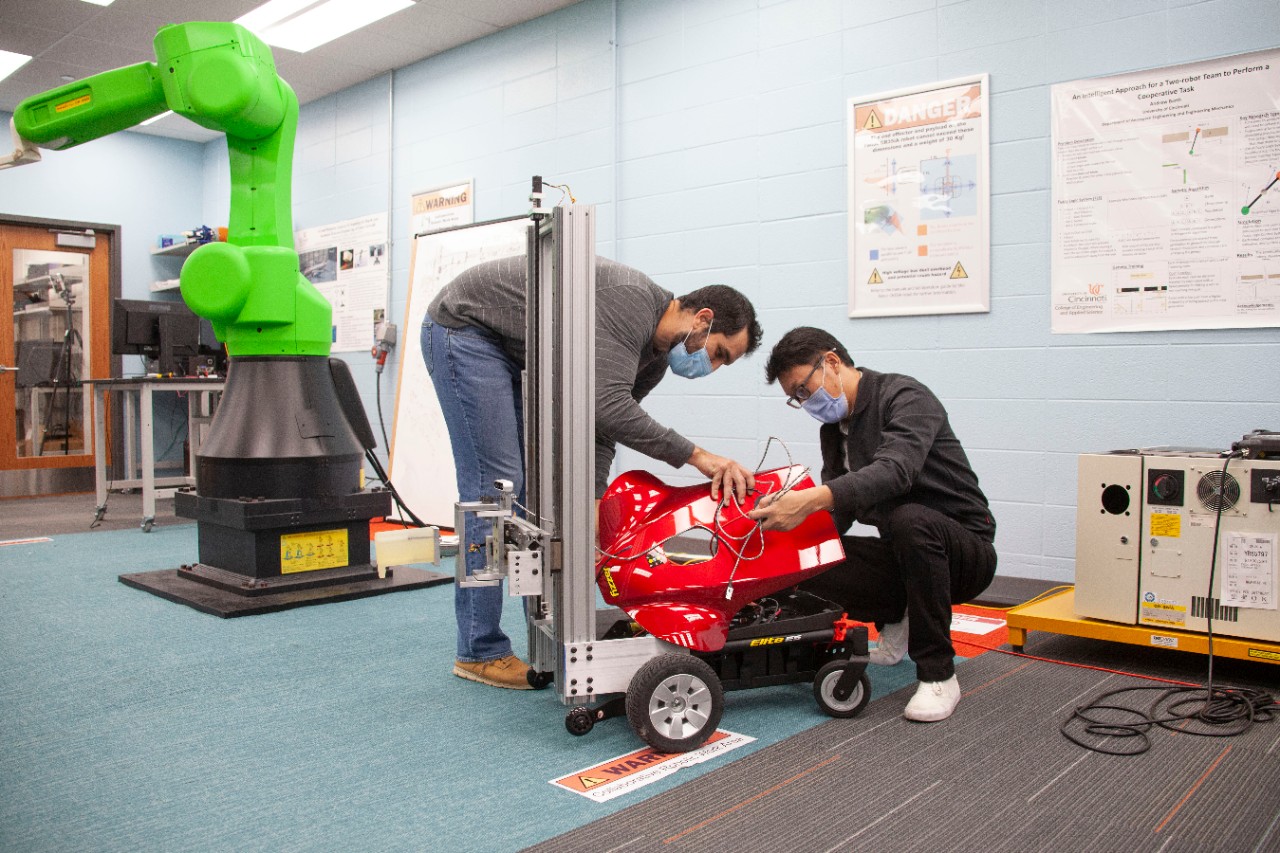 UC students Yufeng "Eric" Sun and Samuel King in Ou Ma's engineering lab are developing an autonomous robot that can open doors for itself and plug itself into the nearest wall outlet. 
