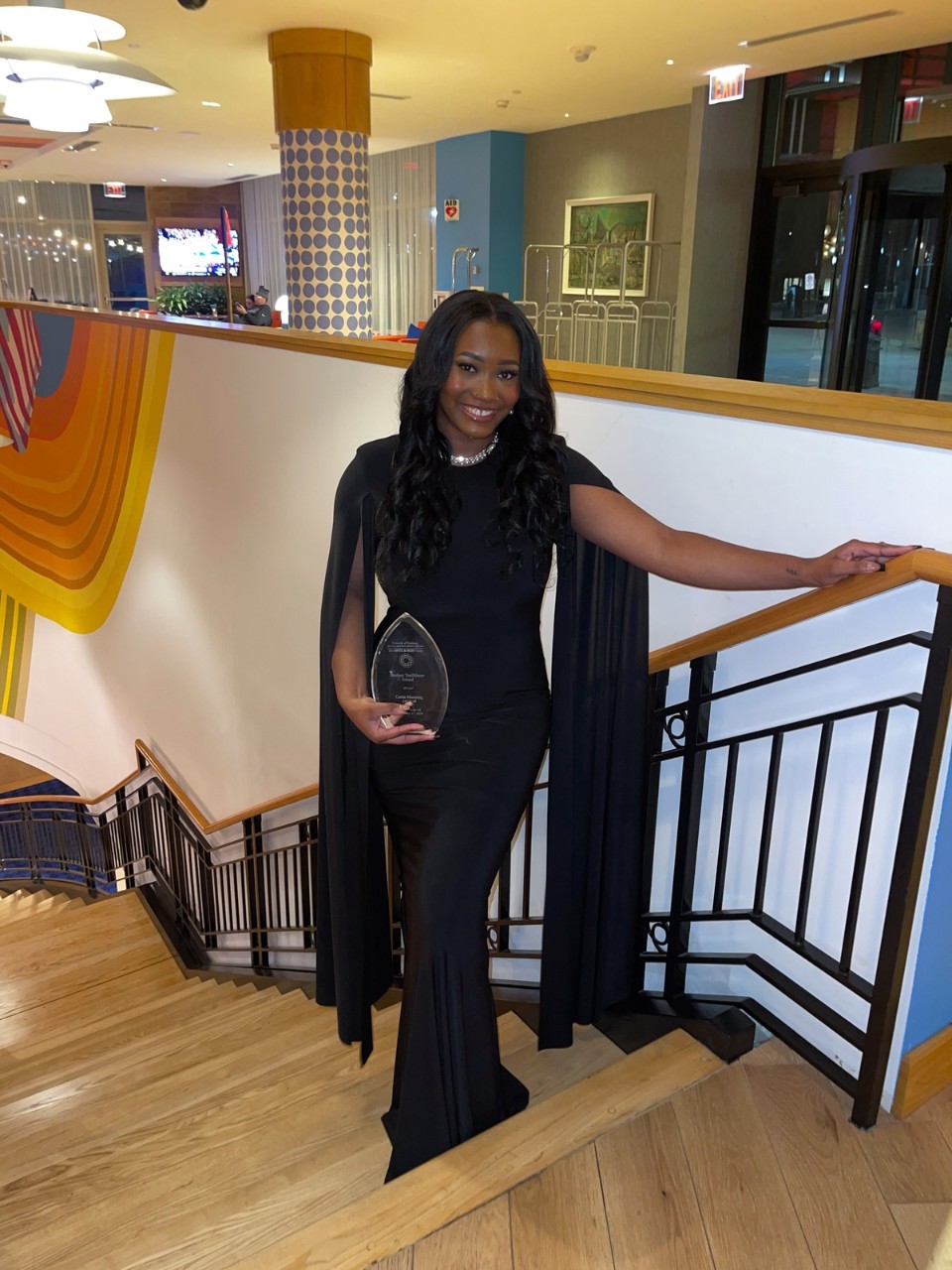 A woman stands on stairs while holding an award.