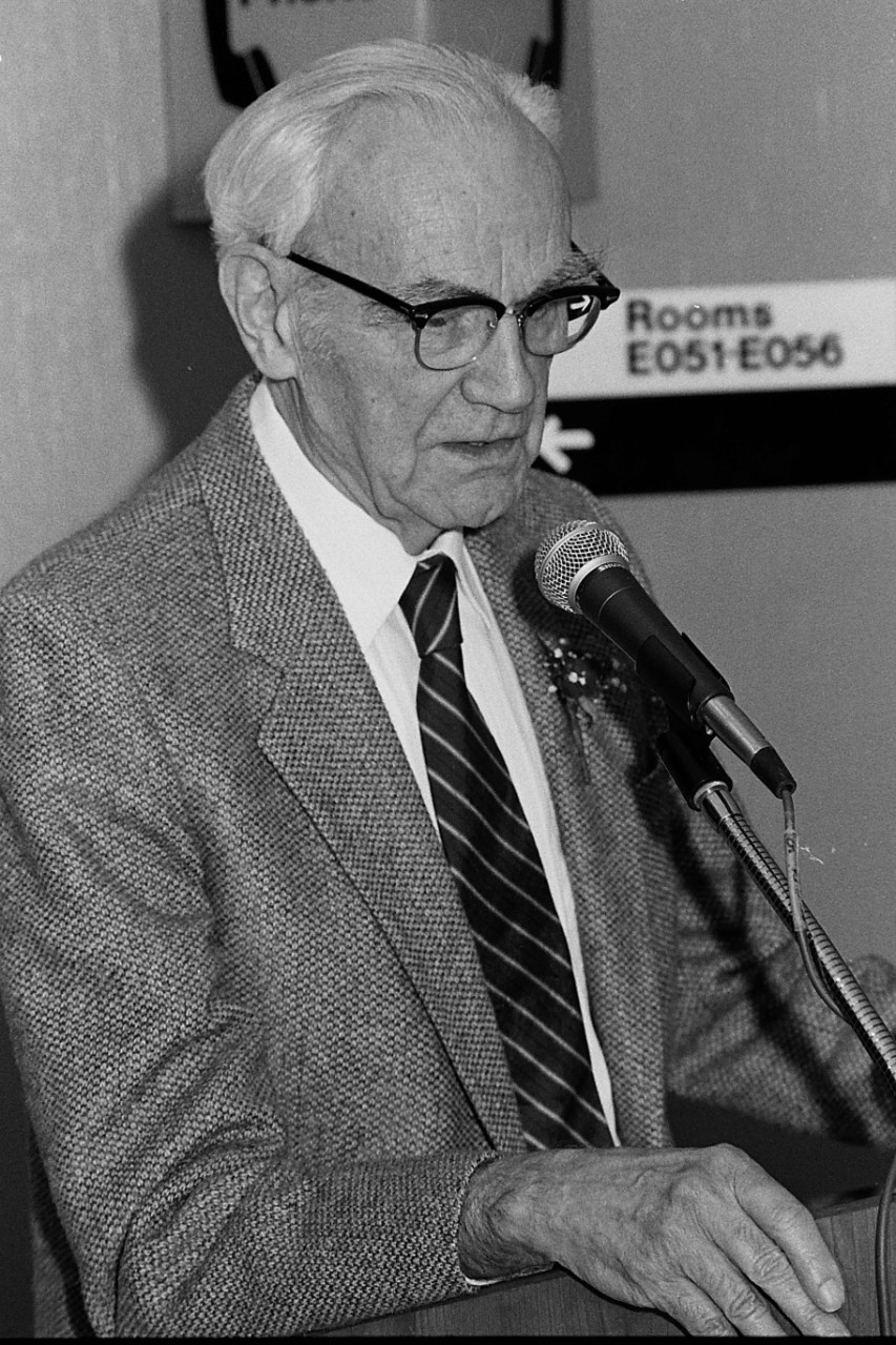 A black and white photo of a man at a lectern