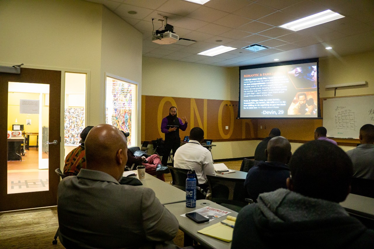 Image of a male presenter speaking with other men seated in the room druing the 2023 Black Male Summit