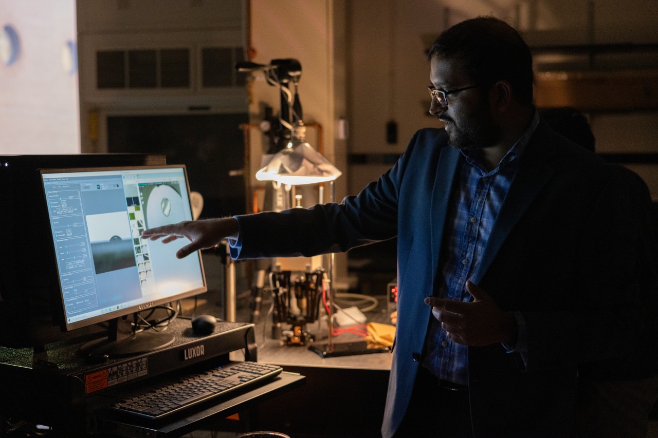 Kishan Bellur points at a computer with data on it