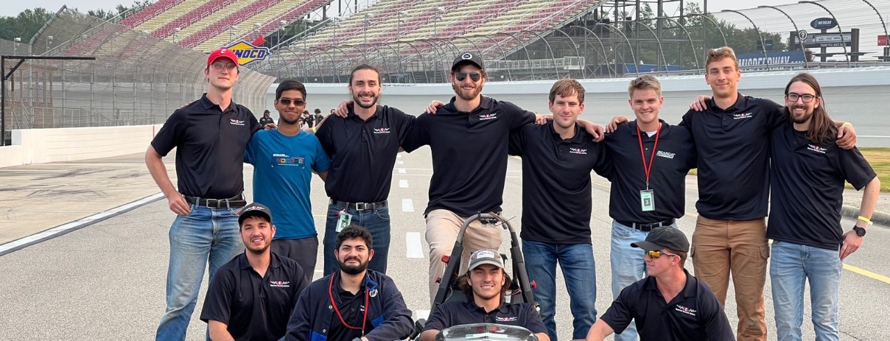 BEV team poses with their car at competition