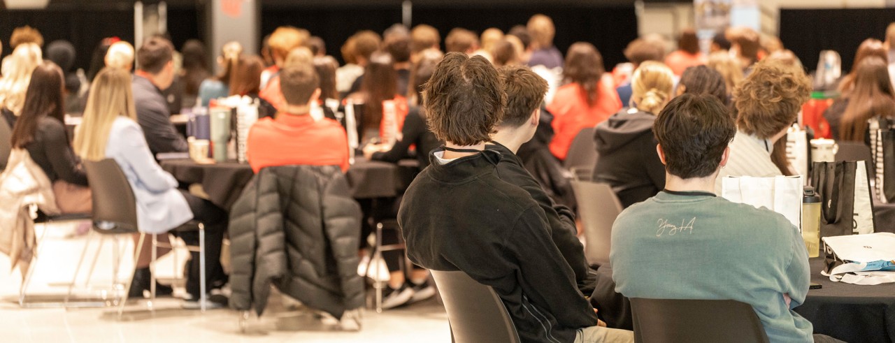Students sitting a room facing a screen at the front of the room