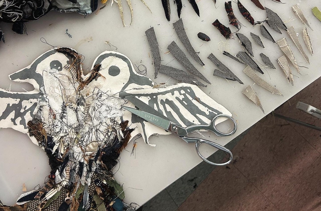 pattern of a bird with wings and feathers cut out of fabric and a pair of scissors 