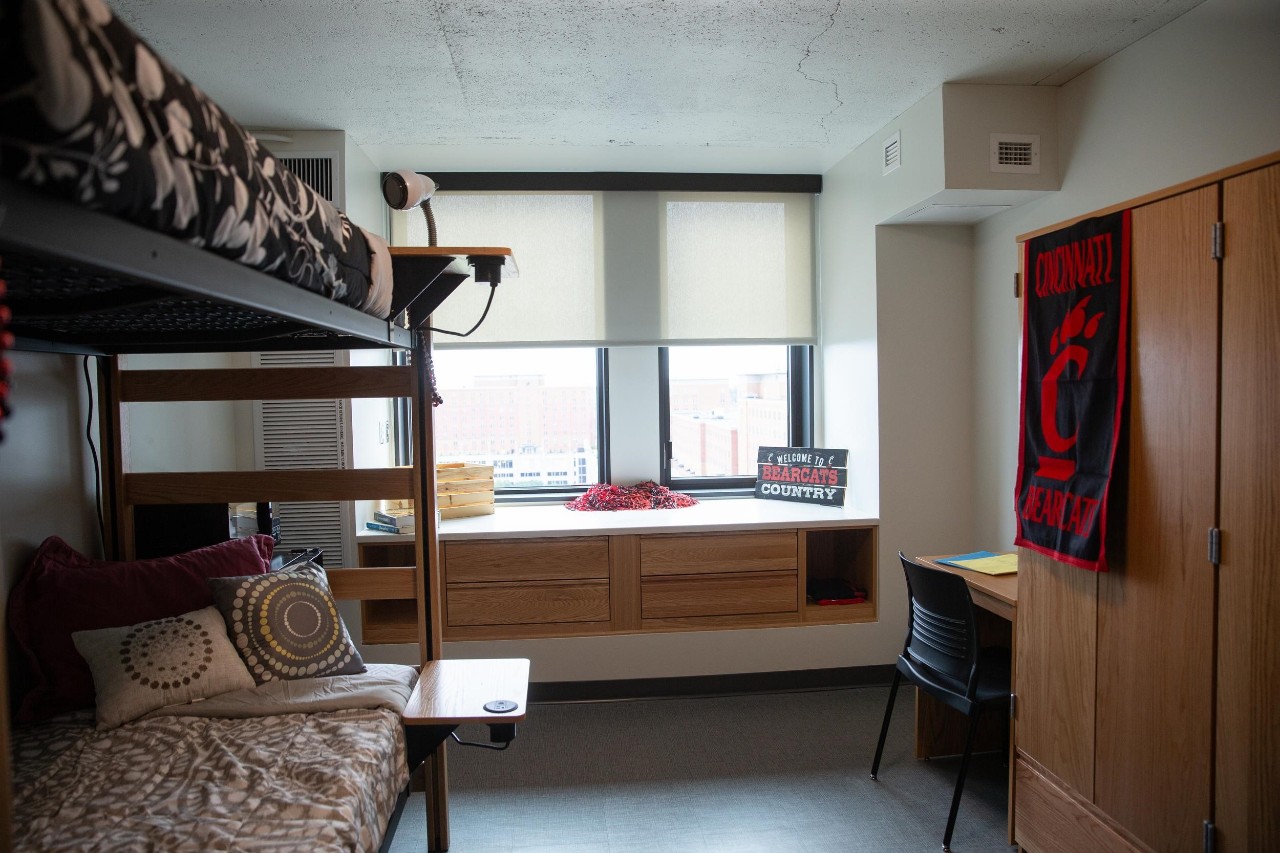 image of a dorm room showing beds, desks, counter and UC branded ware.