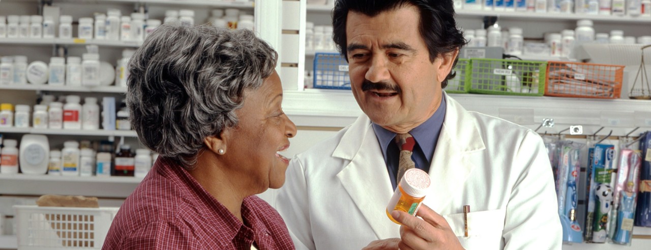 A pharmacist explains a woman's prescription to her. 