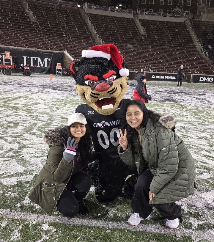 Amrutha and Akshitha Bysani pose with the UC Bearcat on a snowy day at Nippert Stadium.