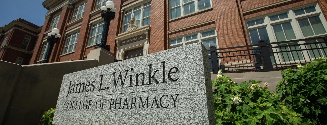 Outside of Kowalewski Hall, a sign reads "James L. Winkle College of Pharmacy"