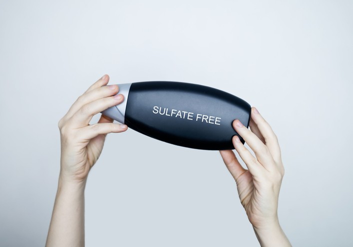 Hands hold a bottle of shampoo that has the words "Sulfate Free" on it