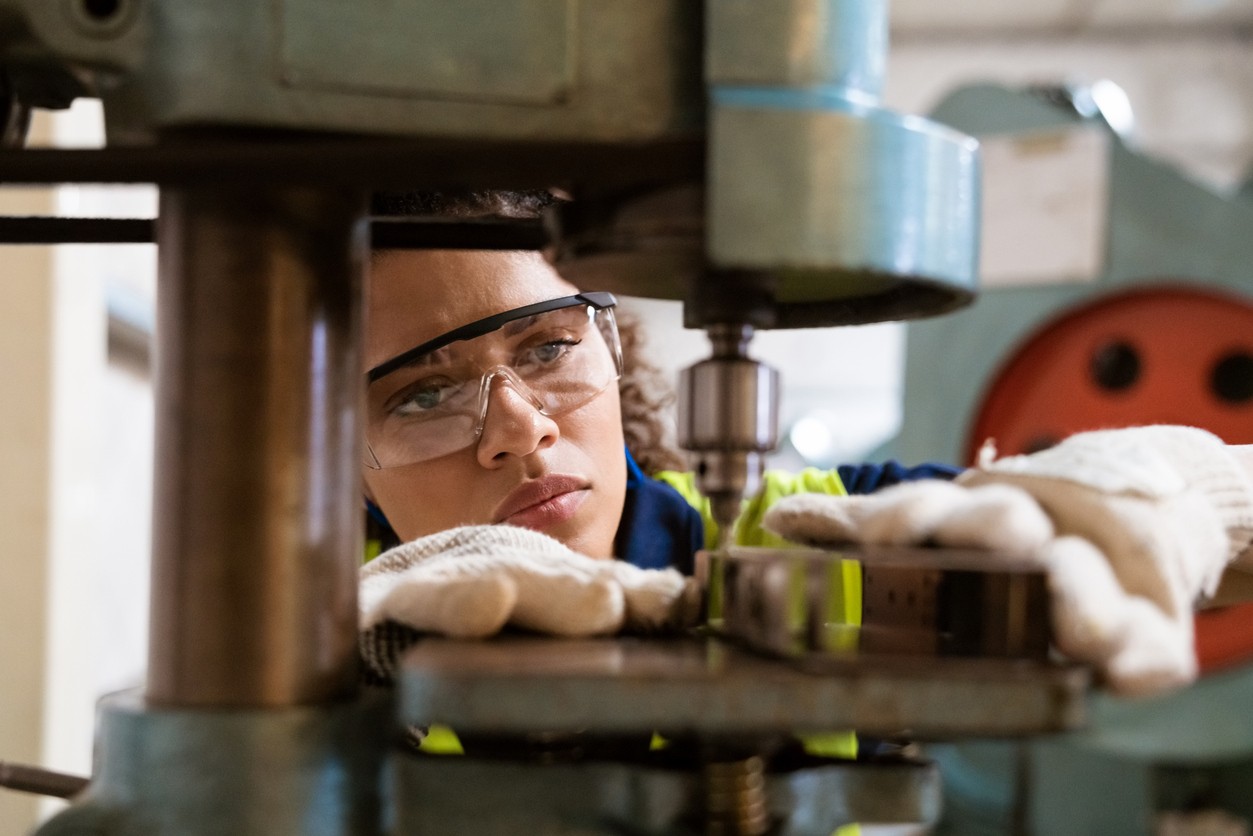 Close-up of female apprentice using yoke machine.