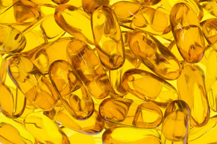 Yellow, translucent oblong omega-3 supplements on a yellow background