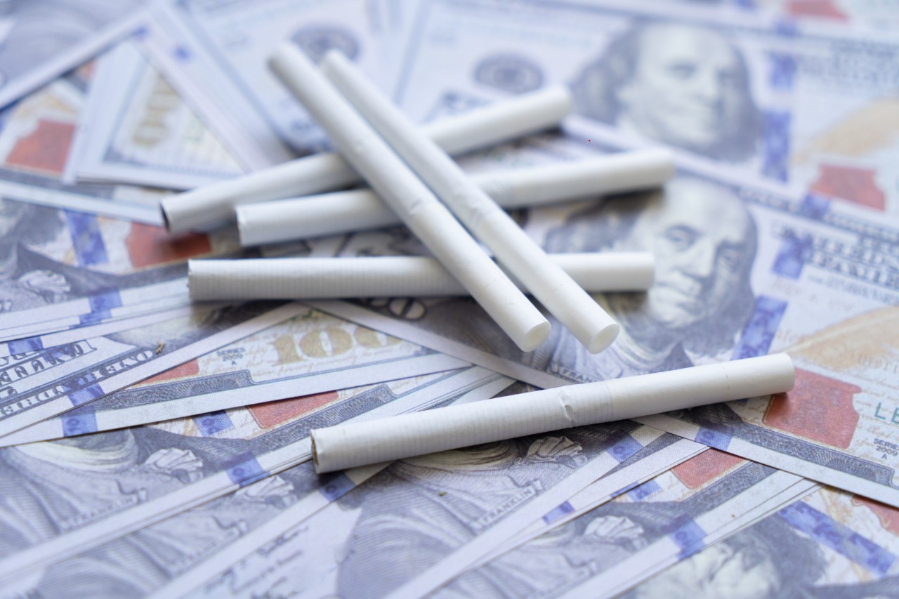 image of several cigarettes laying on dollar bills