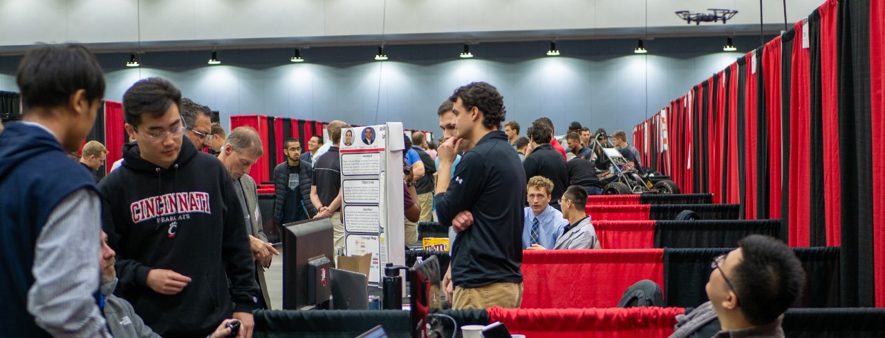 Students stand around their booths at the CEAS EXPO preparing to present 