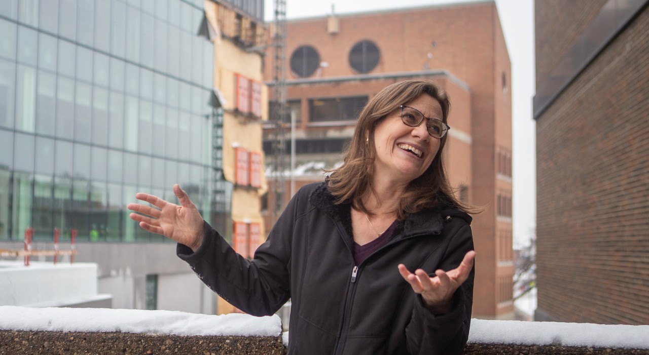 Theresa Culley gestures while talking in front of Old Chem's bird-safe glass windows.