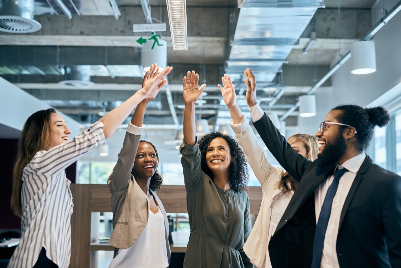Five employee raise their hands for a high-five congratorly minute in a business setting