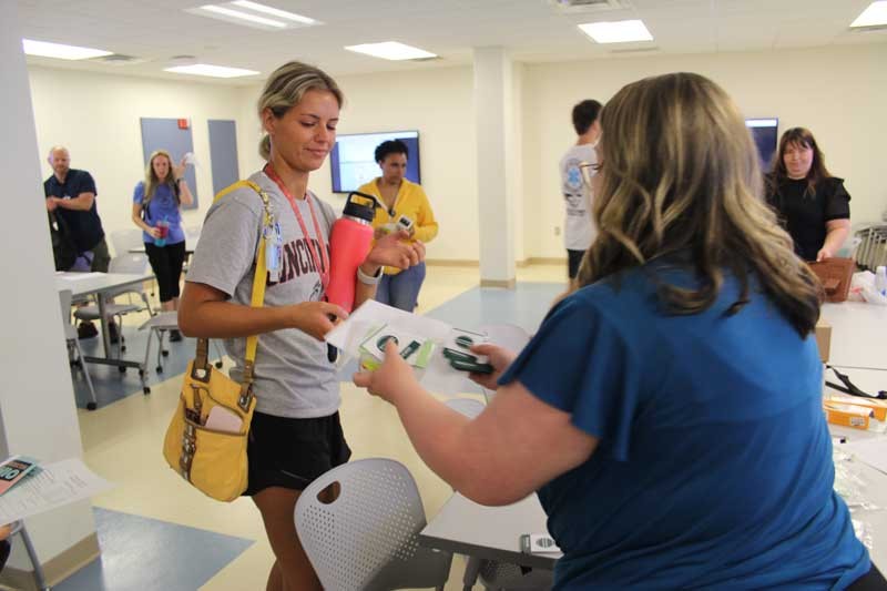A nursing student accepts literature from a nurse at a seminar.