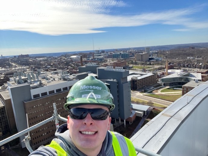 man in hard hat with a building behind him