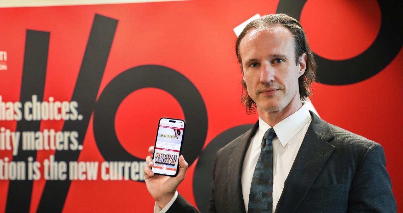 Dylan Steen, MD, holds iphone with High Enroll app displayed.