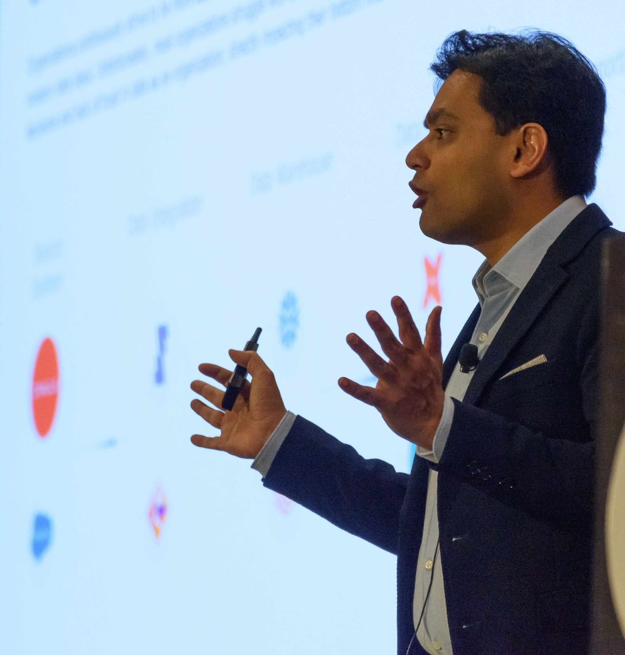 Shashank Sexena presents to a crowd, standing in front of a large screen.