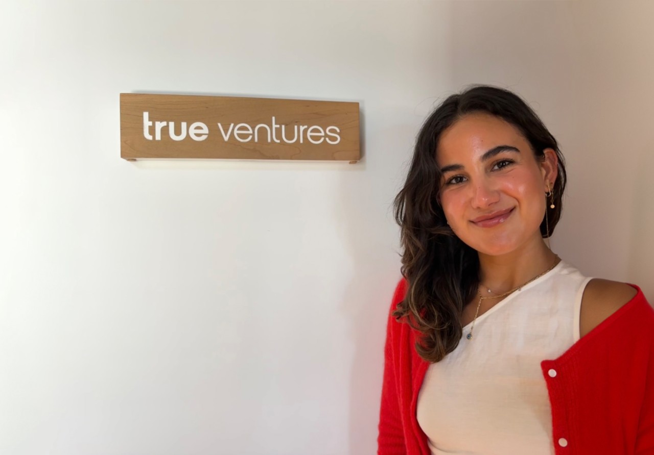 Yasmine Shaban wearing a white shirt and red sweater.