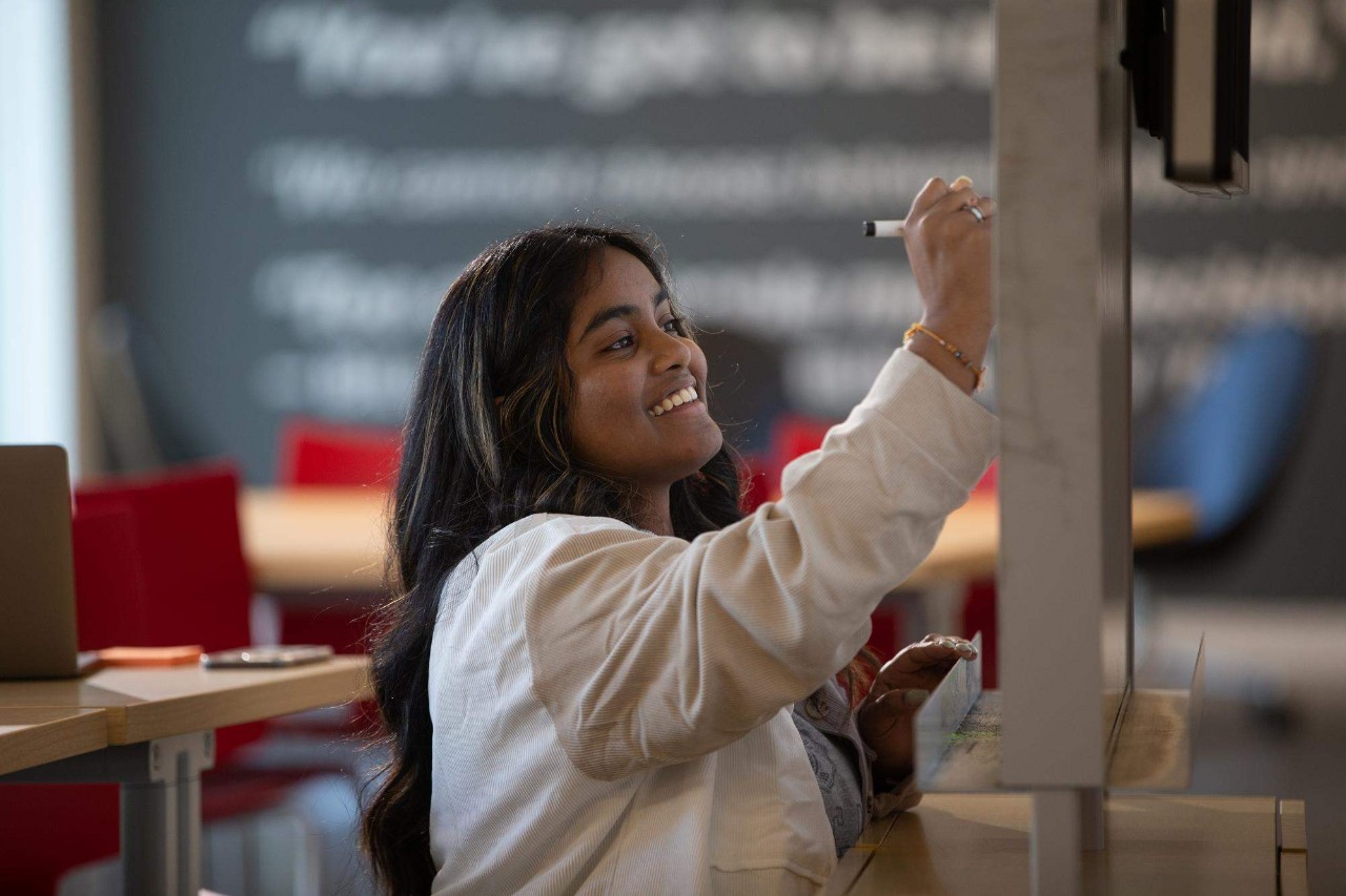A business student writes on a chalkboard