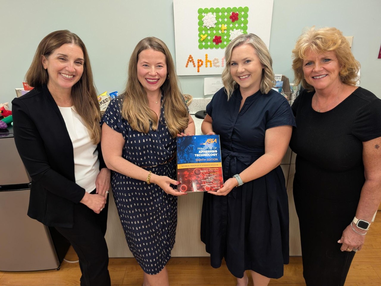 Apheresis employees pictured with the book they helped write