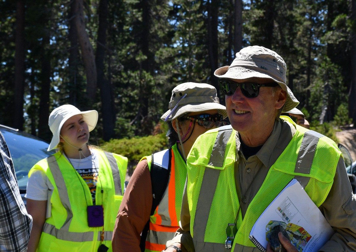 Craig Dietsch talks to students wearing a neon safety vest.