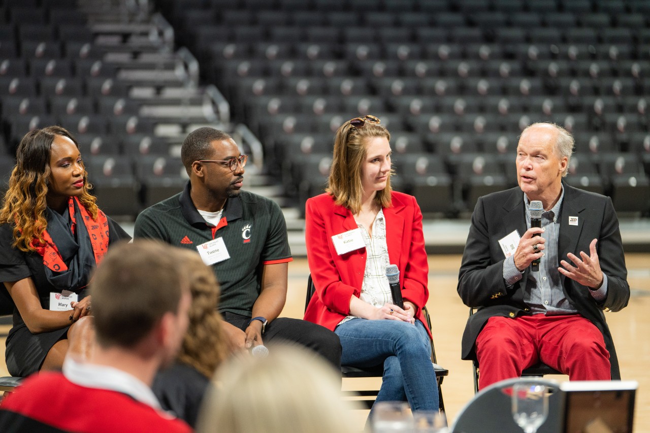 Bill Mulvihill speaking on a panel at 'Dinner with 200' with three other panelists.