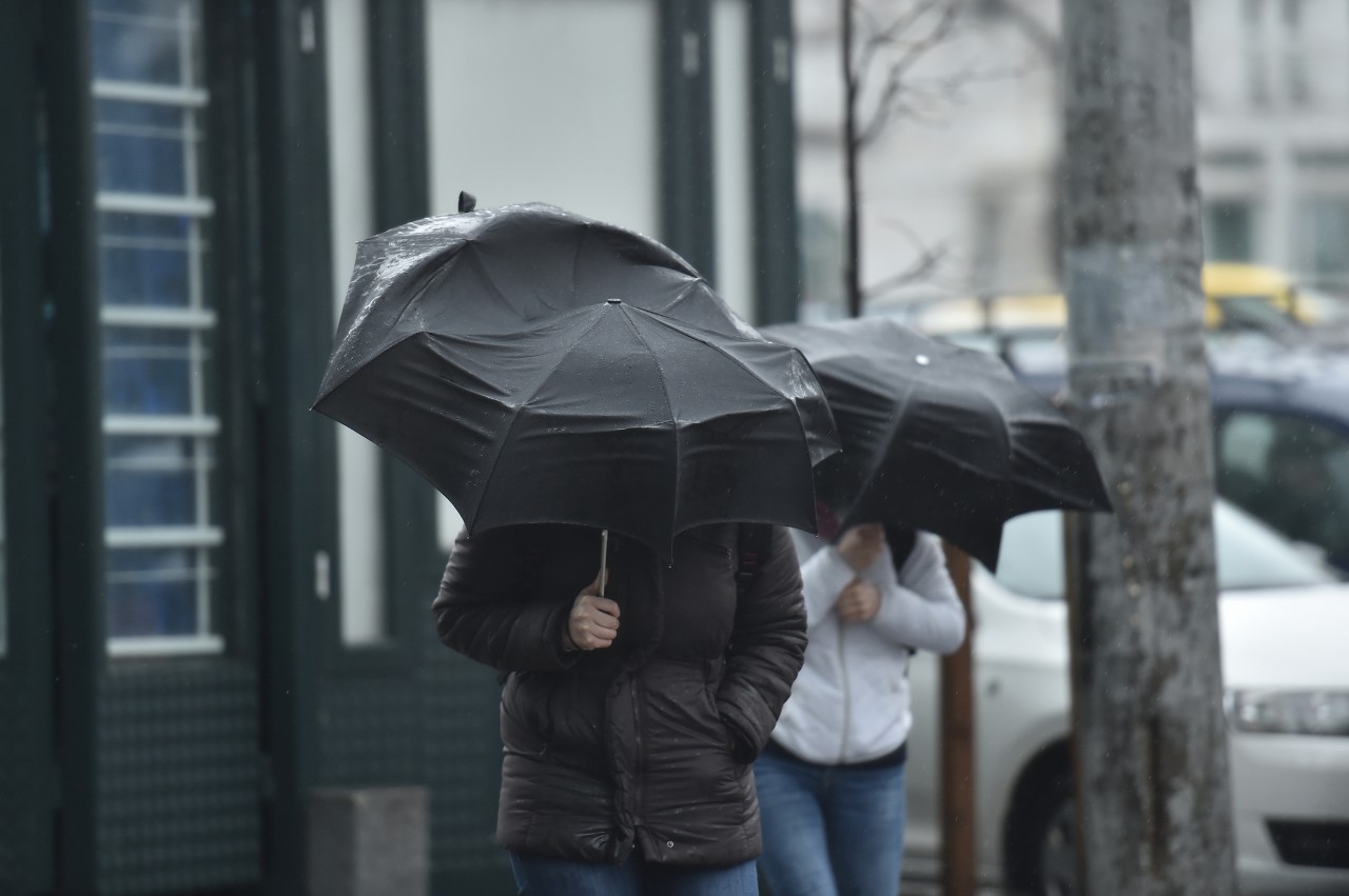 People walking while huddled under umbrellas on a rainy and stormy day 