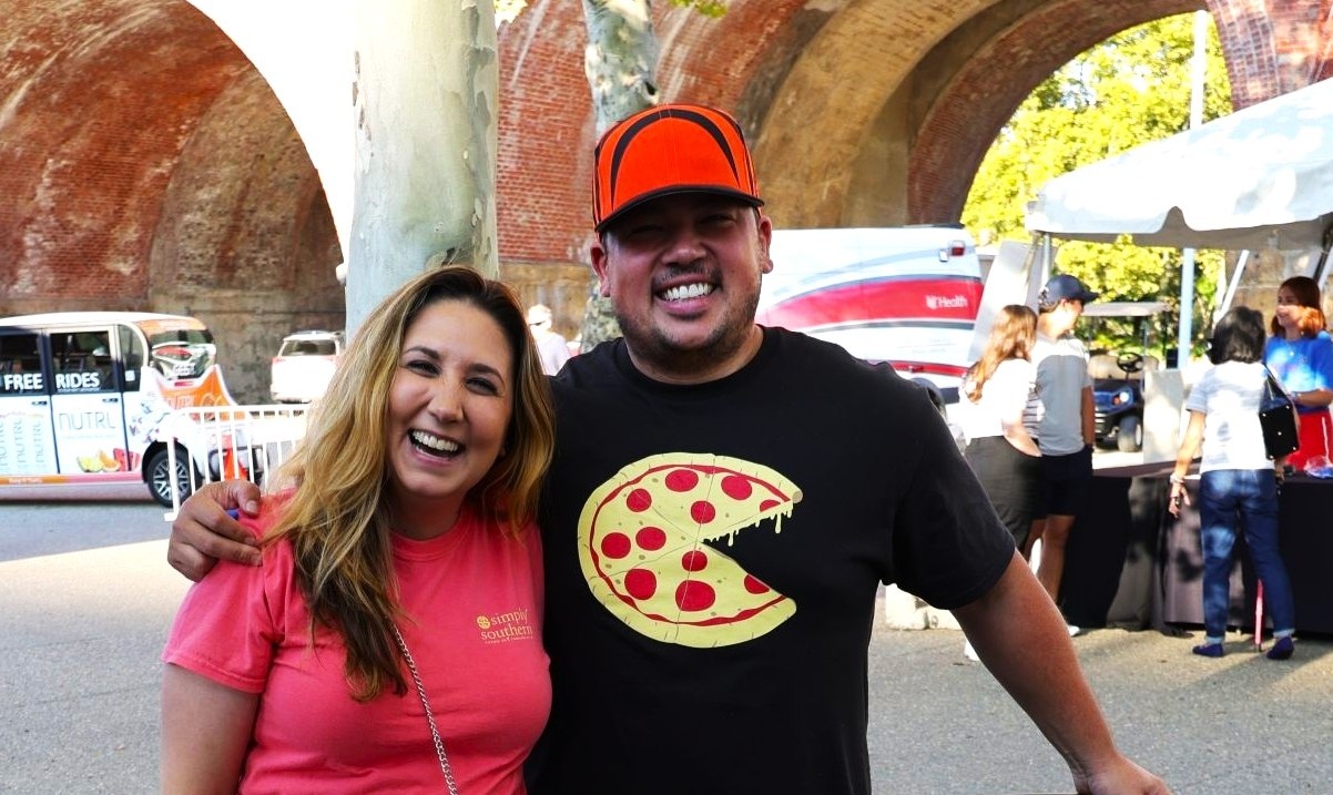 Two smiling people. One is wearing a shirt with pizza on it.