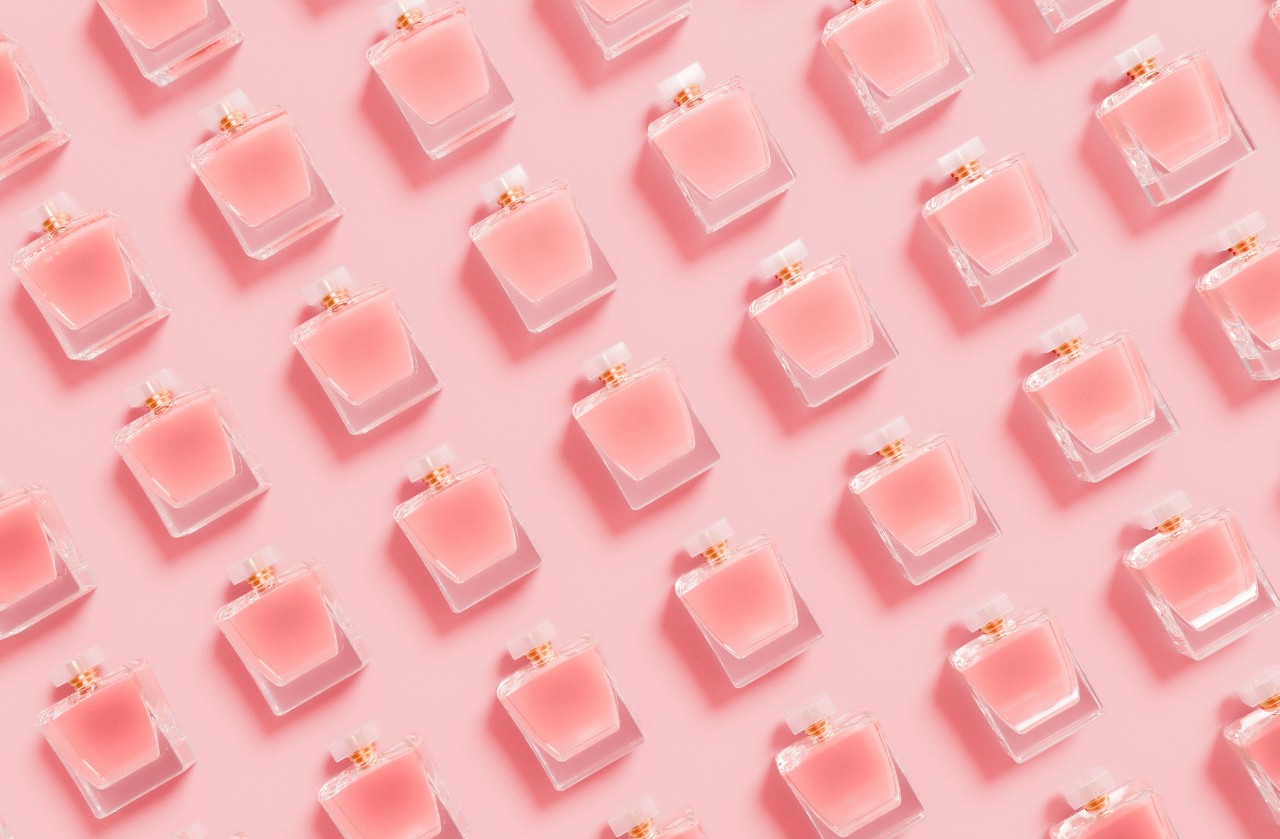 Many perfume bottles lined up on a pink background