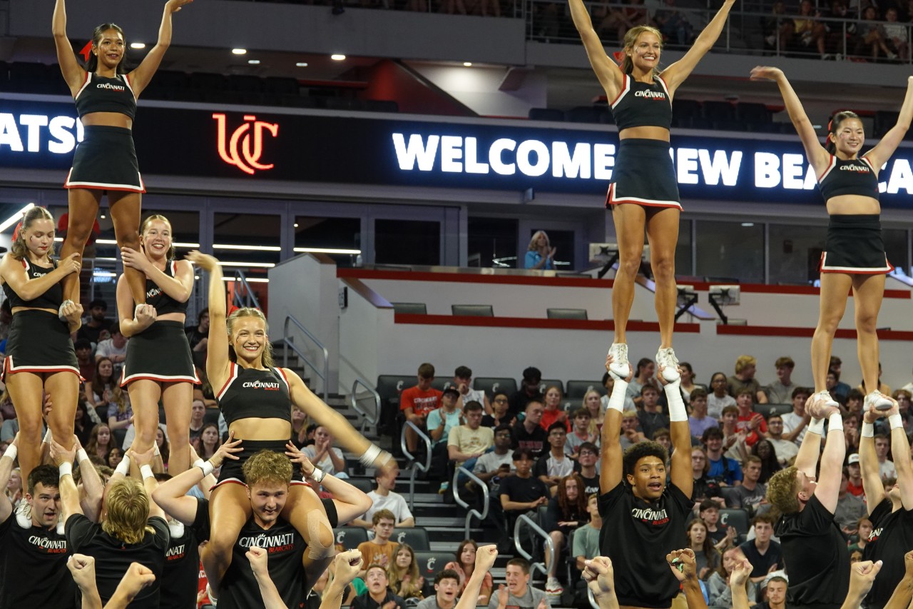 Cheerleaders get hoisted into the air on the floor of Fifth Third Arena.