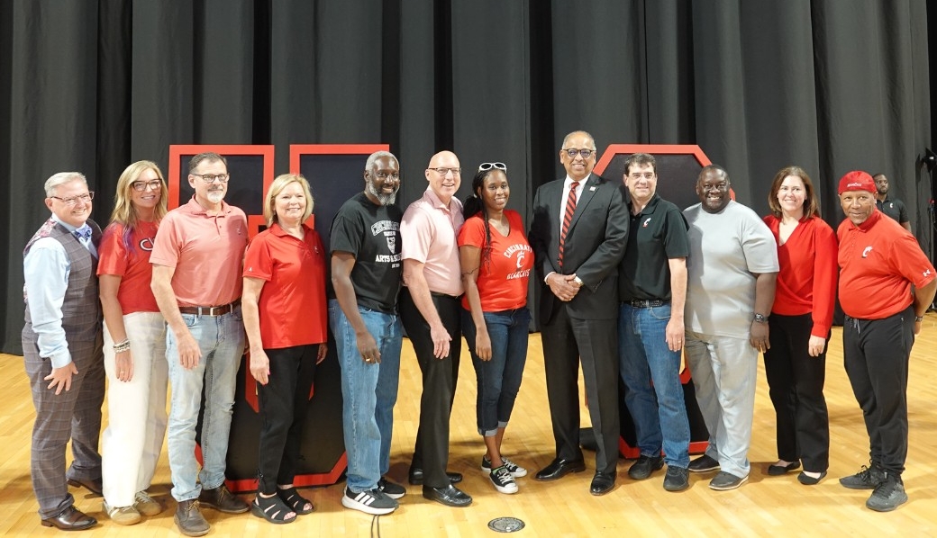 UC deans and administrators pose on stage.