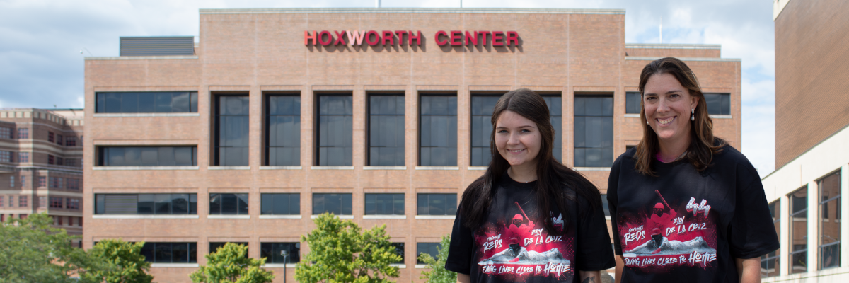 Two people in Elly De La Cruz shirts stand outside Hoxworth Center