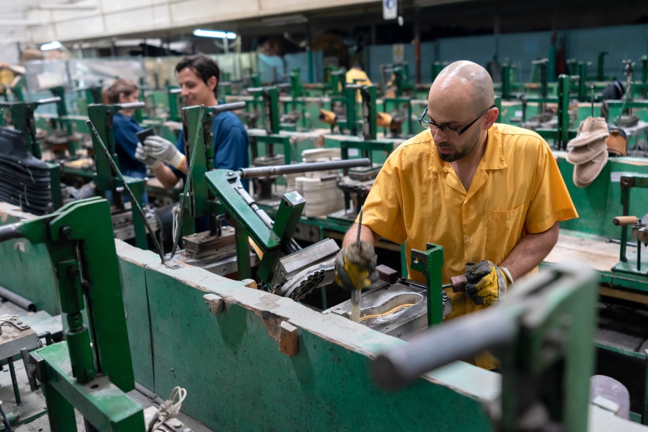 image of three workers in a factory making shoes